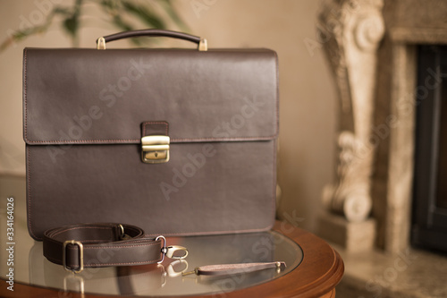 Handmade leather men's briefcase for documents with a brown belt and a pierced lock and key. Work accessory for men