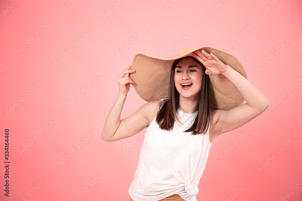 Portrait of a young woman in a large summer hat, on a pink background . Portrait of a young woman in a large summer hat, on a pink background .