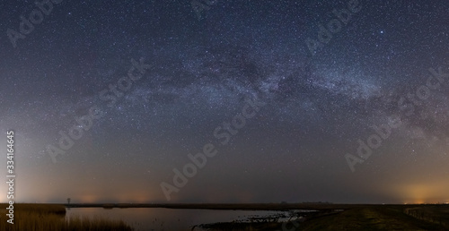 Panaroma shot of the milky way with a moor and reeds in the forground