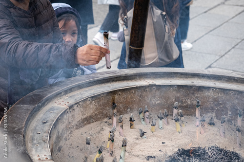 Fotografie, Obraz Japan, Tokyo Hot Spot, Close up, Woman hand going to put the incense sticking in a incense burner bowl at Sensoji Temple, Asakusa Kannon Temple