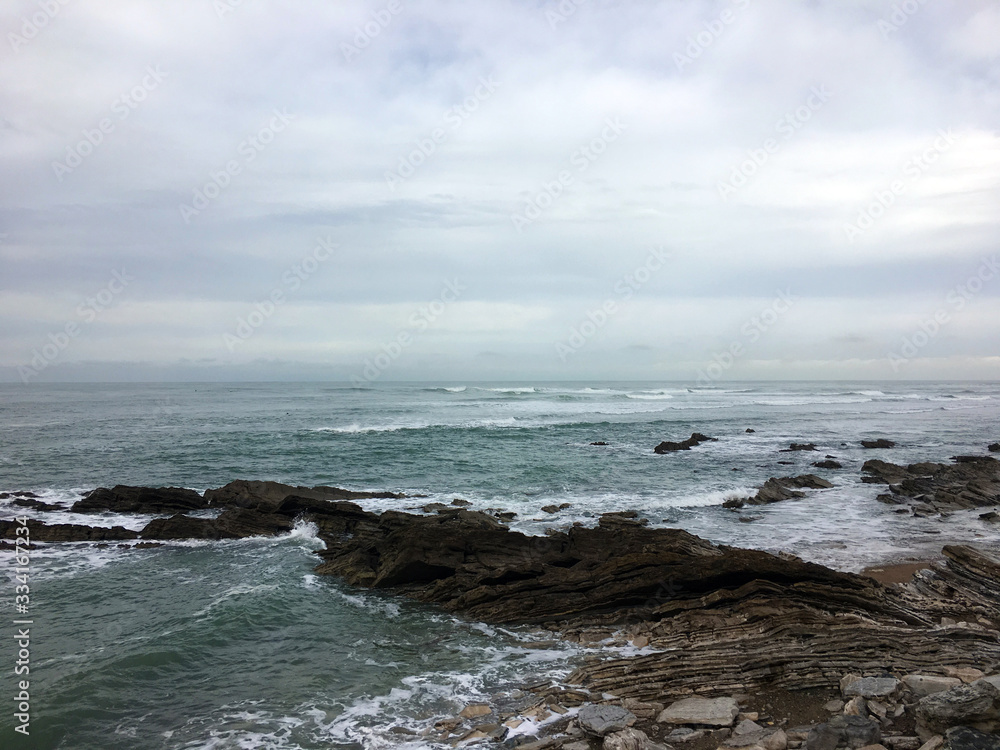 Waves crashing on rocks with cloudy weather