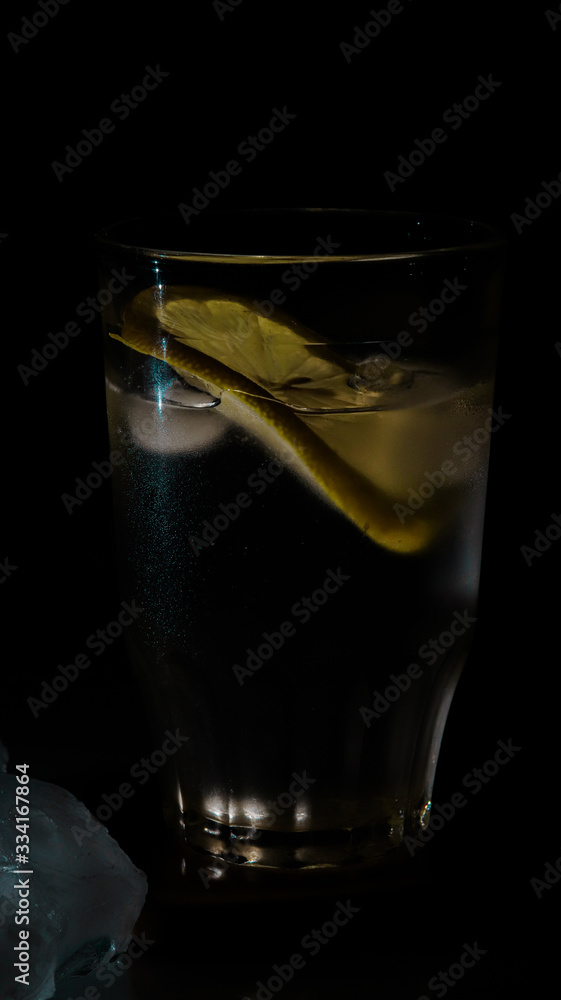 glass of water with lemon and ice on black background glass of water with lemon and ice on black background
