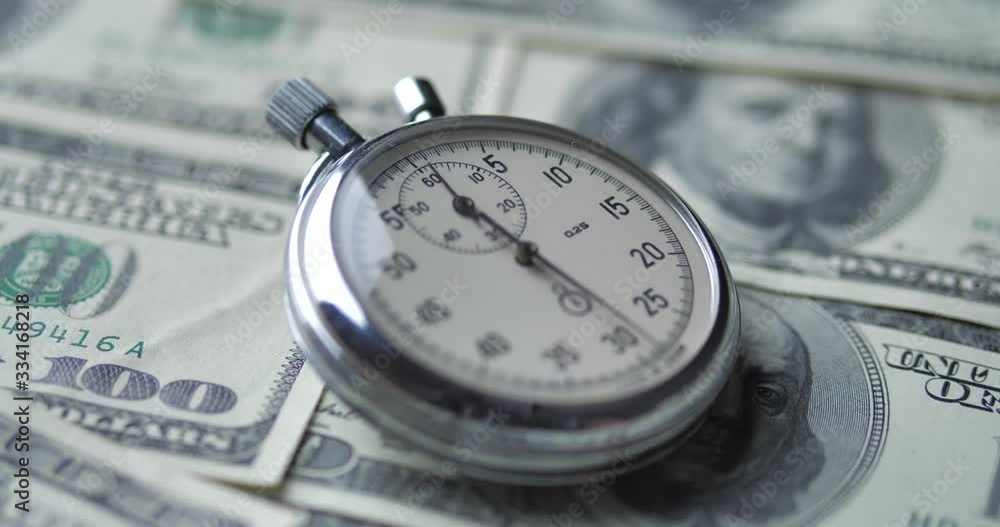 The stopwatch lies on the dollars. Time is money concept. The stopwatch lies on the dollars. Time is money concept.