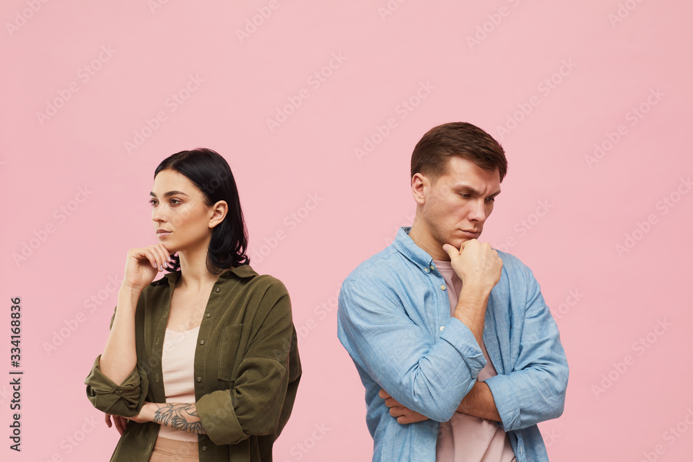 Waist up portrait of frustrated couple standing back to back against pink background, copy space Waist up portrait of frustrated couple standing back to back against pink background, copy space