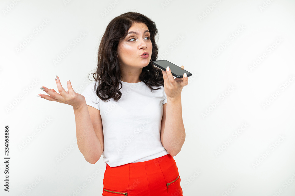 girl with a displeased face talking on the phone over the speakerphone and swears on a white background girl with a displeased face talking on the phone over the speakerphone and swears on a white background