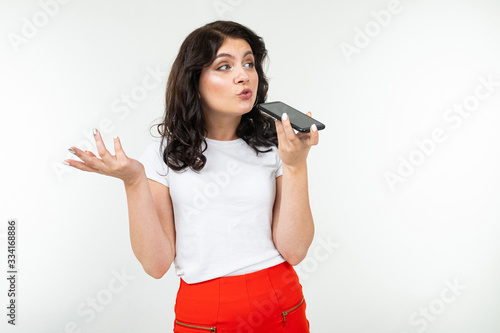 girl with a displeased face talking on the phone over the speakerphone and swears on a white background