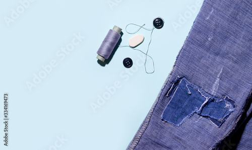 Canvas-taulu Threads and buttons on a blue background next to jeans