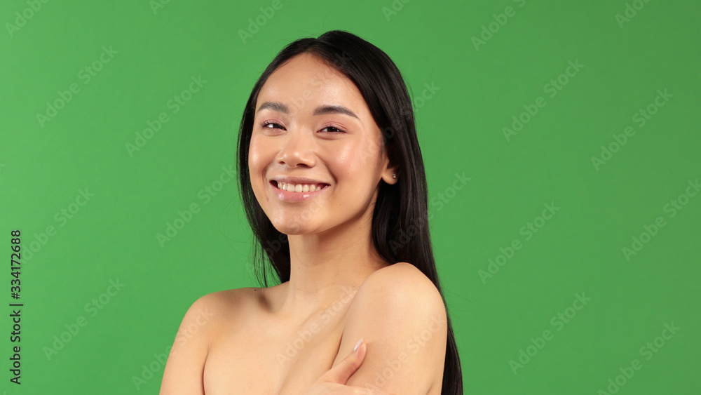 Obraz premium Close-up of asian beauty woman skin care. Beautiful young woman looking at camera and smiling. Isolated on green background. Asian Caucasian mixed race model