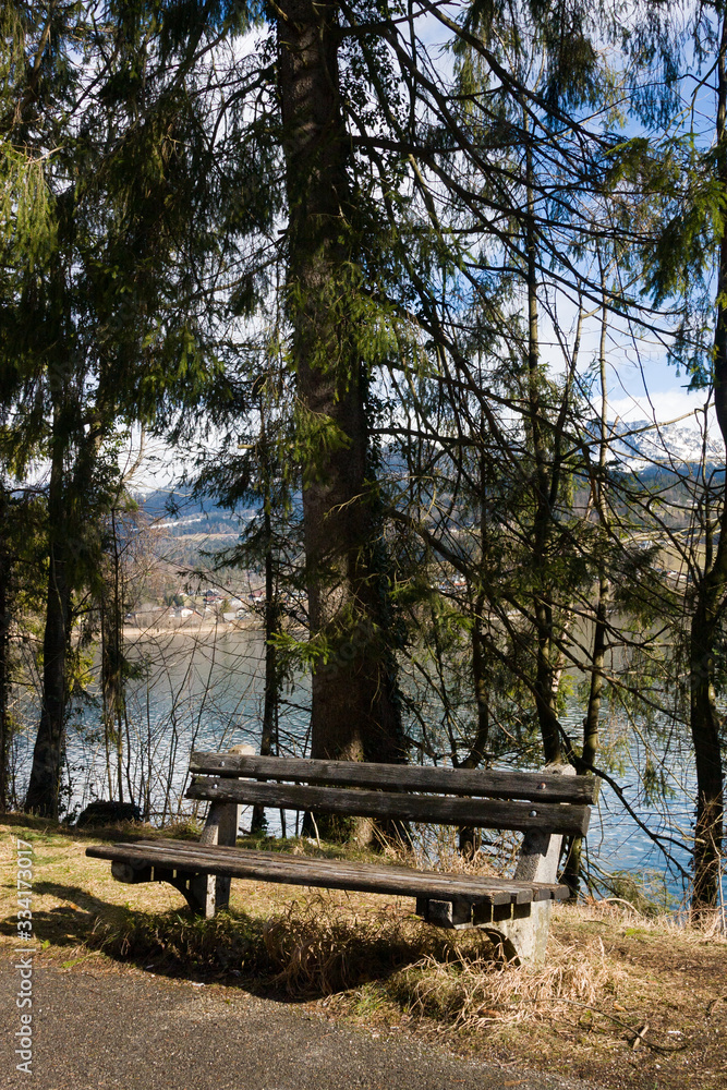 Empty wooden bench on shore of beuatiful lake in austrian Alps. Winter sunny morning on lake Hallstatt. The most beautiful lake to explore in Austria. Empty wooden bench on shore of beuatiful lake in austrian Alps. Winter sunny morning on lake Hallstatt. The most beautiful lake to explore in Austria.