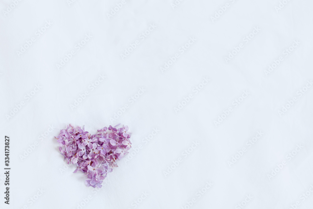 Fototapeta premium Lilac flowers mock up on white textile background. Little love heart on white texture background template. On the left down side 