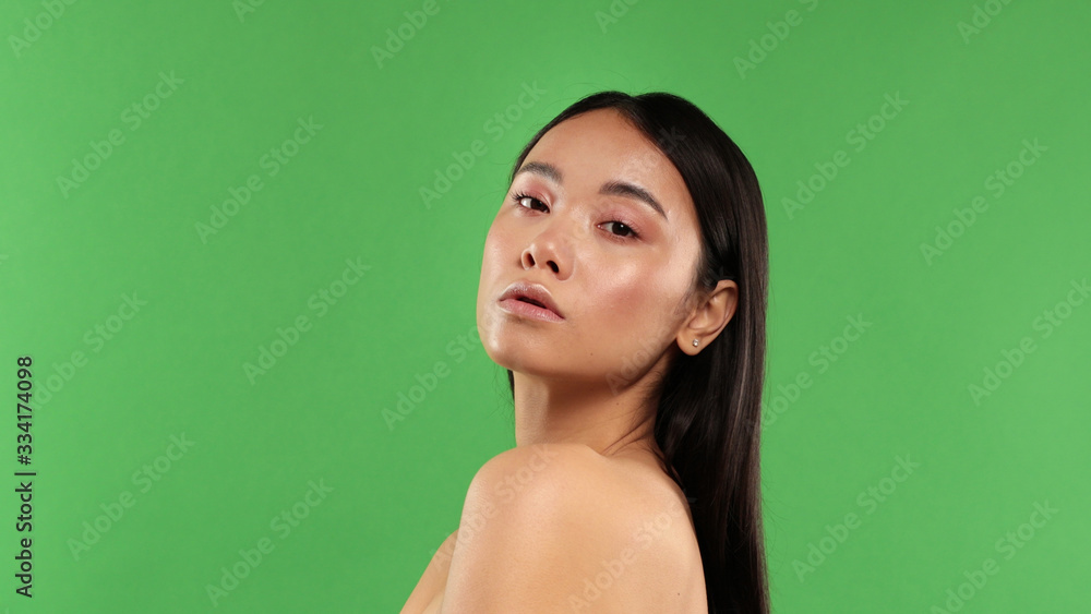 Beautiful exotic young woman bare back and shoulders isolated against green Beautiful exotic young woman bare back and shoulders isolated against green