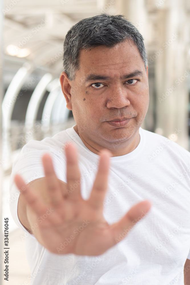 old man showing rejecting, stopping hand gesture; concept of forbidding, no way, rejection, negative answer, halt, stop, warning, social distancing; southeast asian senior old man model old man showing rejecting, stopping hand gesture; concept of forbidding, no way, rejection, negative answer, halt, stop, warning, social distancing; southeast asian senior old man model