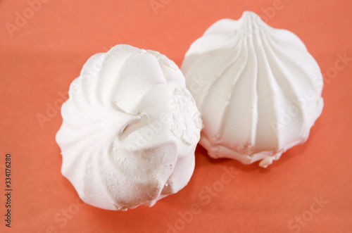 two white marshmallows on a pink background. Close-up.