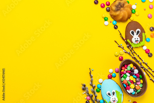 Colorful Easter BAckground. Chocolate Eggs and Candy on Yellow Background. Copy Space on Flat Lay Design