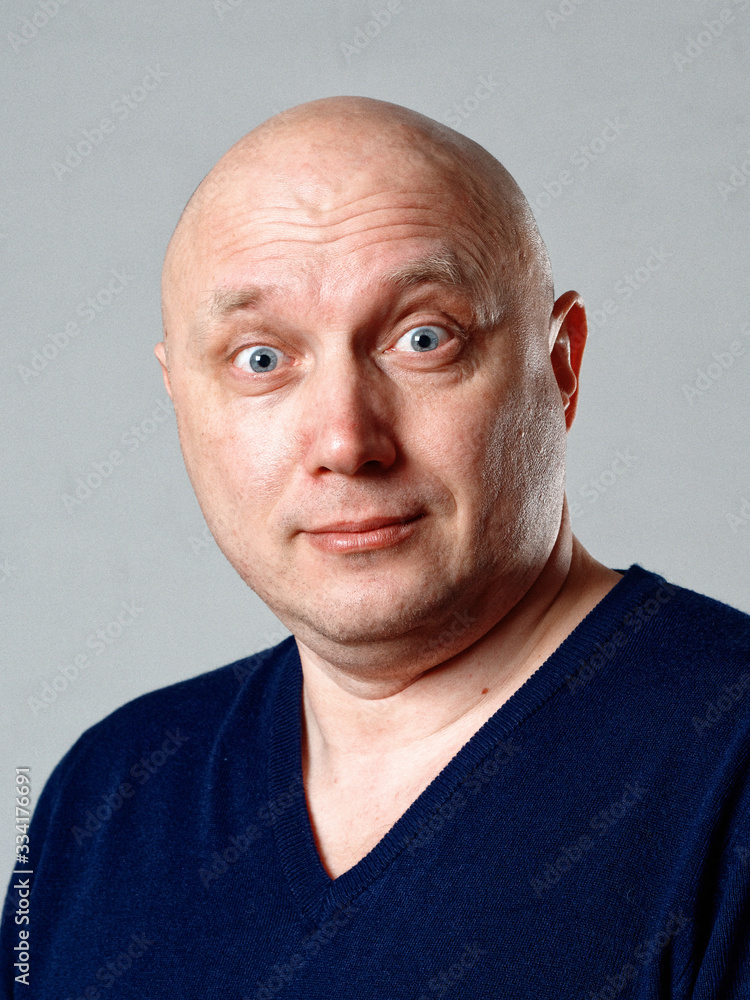 Fototapeta premium Portrait of a bald cheerful man on a gray background