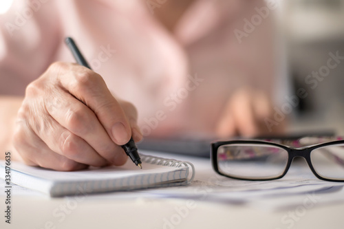 Pension calculation concept, old hands counting finances on a home calculator , close- up