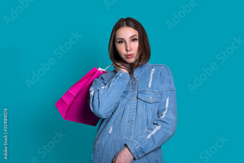Portrait of a smiling pretty girl with shopping bags over blue background. Black friday concept.