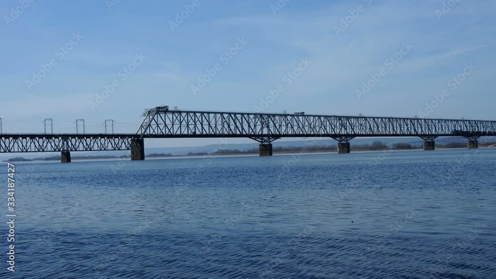 freight train rides over the bridge.Railway bridge over the river. Sunny spring day. freight train rides over the bridge.Railway bridge over the river. Sunny spring day.