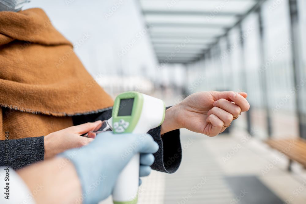 Measuring body temperature with infrared thermometer at a checkpoint during a virus outbreak, close-up on hand. Concept of prevention the spread of the virus