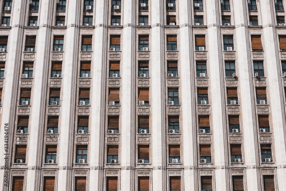 Fototapeta premium The exterior of an old soviet era style building with window air conditioning machines.