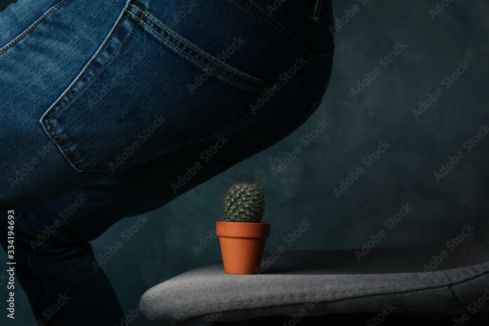Man sit on a chair with cactus. Hemorrhoids