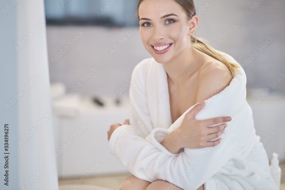 Beautiful young woman in bathrobe resting on bed after shower at home Beautiful young woman in bathrobe resting on bed after shower at home