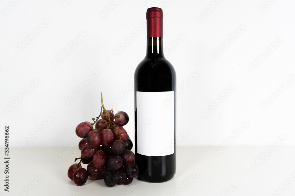 Obraz premium Set of red wine with white mockup label accompanied by table red grapes