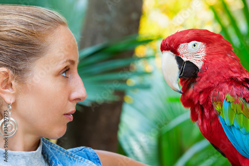 Photography Face portrait of young girl looking at red macaw parrot