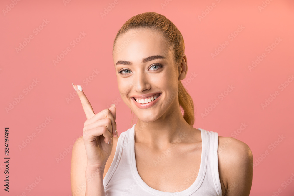 Happy Girl Applying Facial Cream Standing Over Pink Background, Studio Happy Girl Applying Facial Cream Standing Over Pink Background, Studio