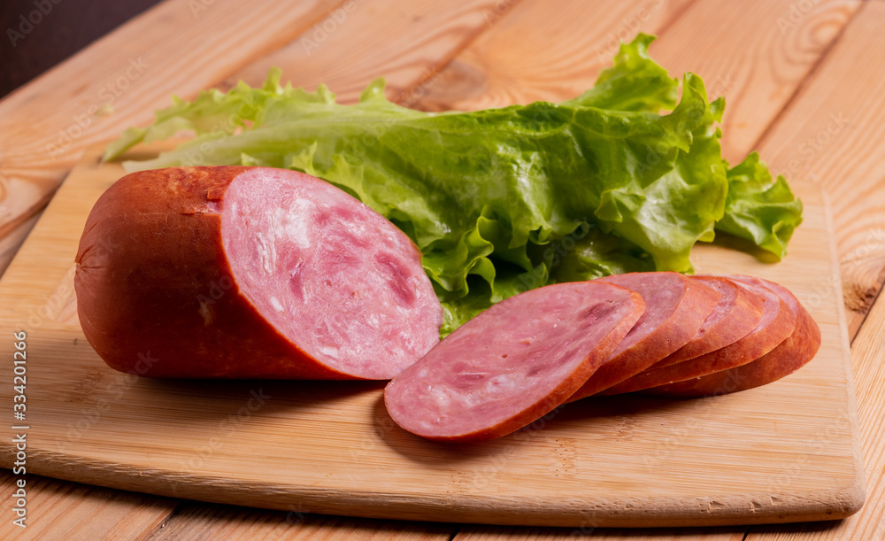 Slices of sausage, wheat bread and lettuce on a plate on the table close-up. Slices of sausage, wheat bread and lettuce on a plate on the table close-up.