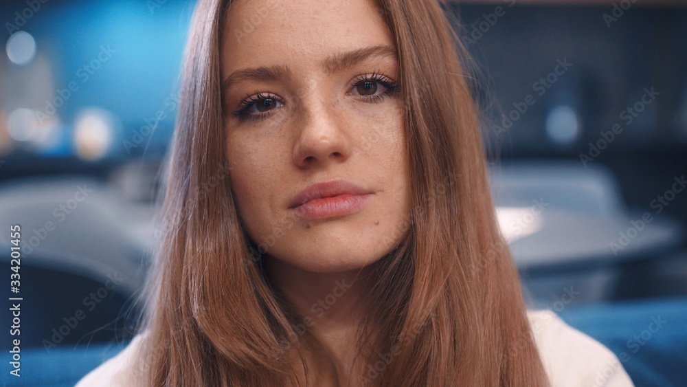 Close up portrait of young charming golden hair woman in white t-shirt with freckles open eyes and looks to camera in modern apartment feeling happy great evening good emitions home comfortable Close up portrait of young charming golden hair woman in white t-shirt with freckles open eyes and looks to camera in modern apartment feeling happy great evening good emitions home comfortable