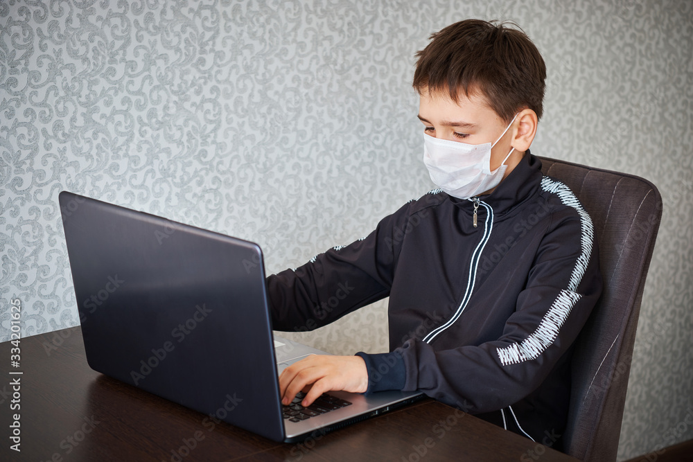 Boy in medical mask at the computer Boy in medical mask at the computer