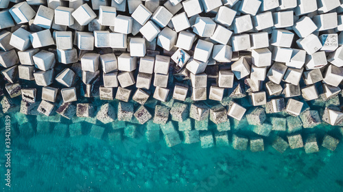 Foto Aerial view of a young man on a cement cube blocks protecting the shore from the waves in the port of Malaga, Spain