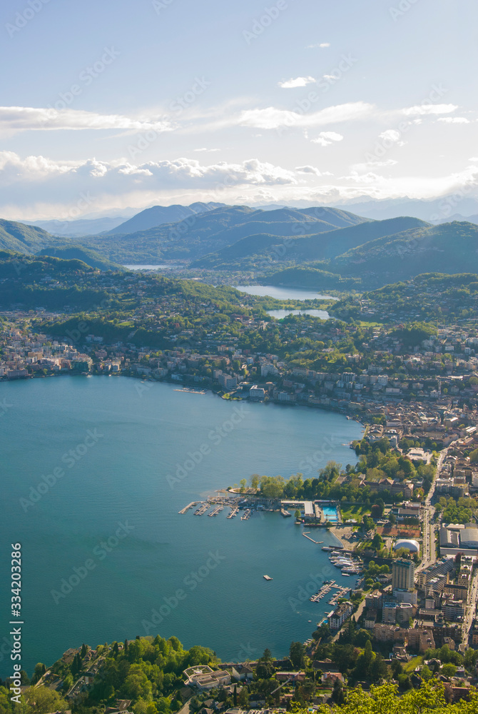 Top view of the city of Lugano, Switzerland from the height of Mount Monte Bre. Beautiful mountain scenery on a sunny summer day. View of Lake Lugano and the Alpine mountains.