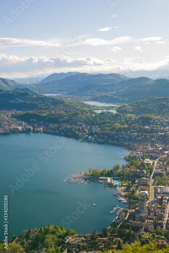 Top view of the city of Lugano, Switzerland from the height of Mount Monte Bre. Beautiful mountain scenery on a sunny summer day. View of Lake Lugano and the Alpine mountains.