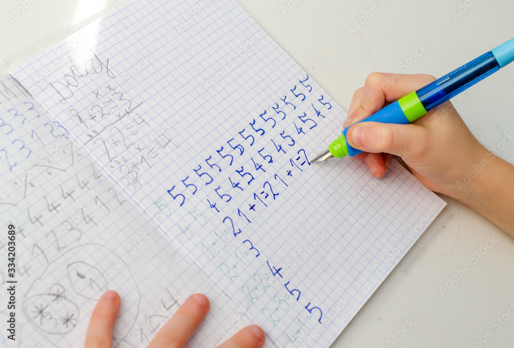Kid hands doing math homework. Close up of young boy hand holding pen and writing a math homework close-up. concept of education at home. Kid hands doing math homework. Close up of young boy hand holding pen and writing a math homework close-up. concept of education at home.