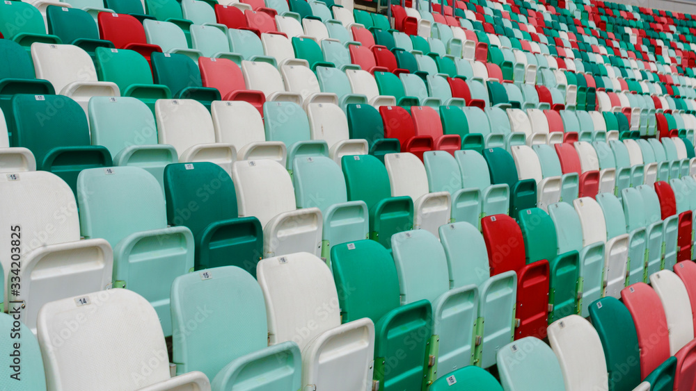 Naklejka premium Close-up empty multi-colored plastic seats with numbers at the stadium. Sport concept.