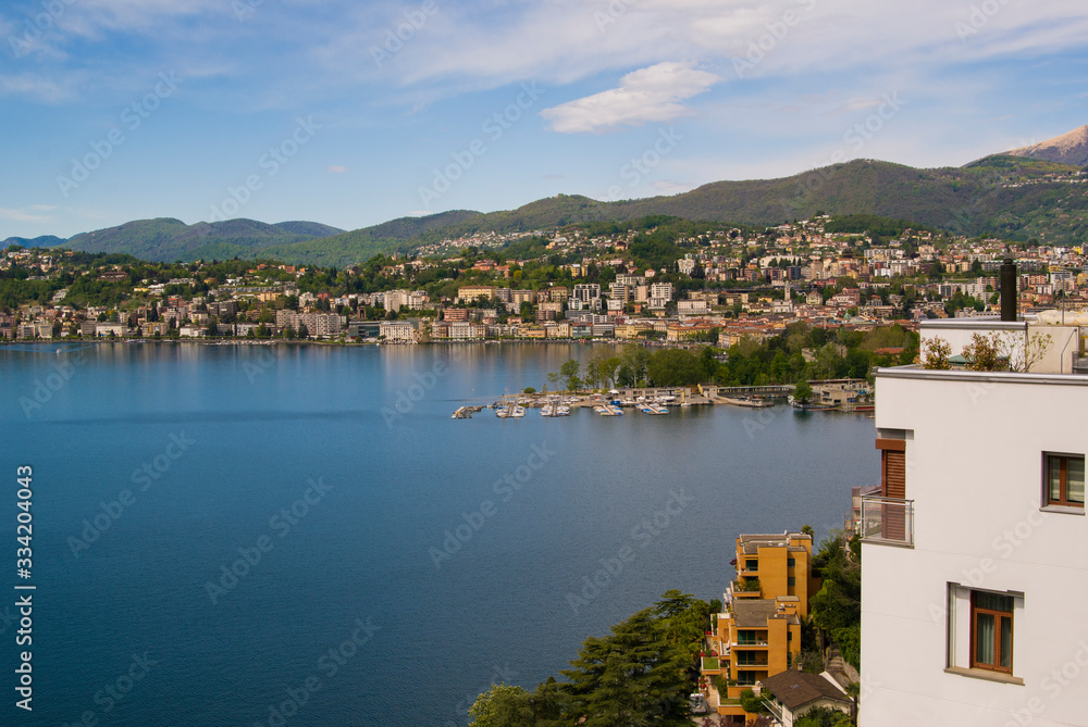 View of the lake and the city of Lugano on a sunny summer day. Mountain landscape in the city of Lugano, Switzerland. 