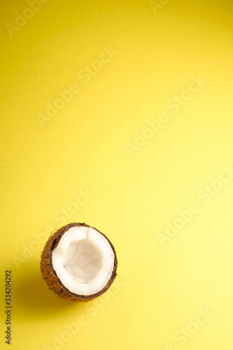 Single coconut fruit on yellow plain background, abstract food tropical concept, angle view copy space © Frostroomhead