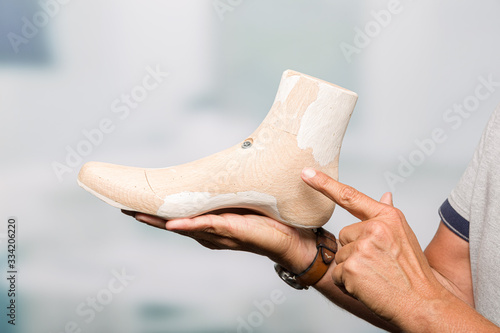 Bild auf Leinwand hands of a orthopedic shoemaker pointing at individual crafted wooden last