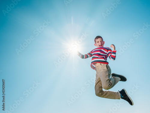 young boy jumping high and reaching the sun