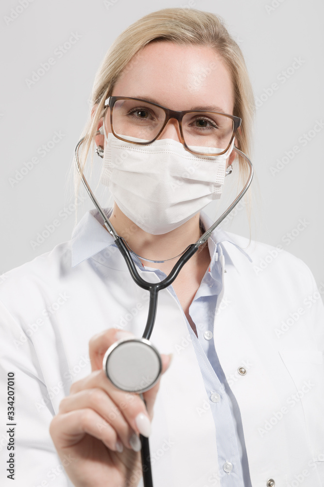 Female family doctor in doctor's overall with stethoscope and medical face mask Female family doctor in doctor's overall with stethoscope and medical face mask