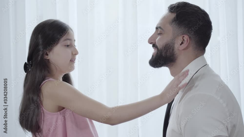 Close-up of cute Middle Eastern daughter fixing father's necktie. Happy little girl helping smiling businessman to get ready for work. Family, unity, lifestyle, care. Close-up of cute Middle Eastern daughter fixing father's necktie. Happy little girl helping smiling businessman to get ready for work. Family, unity, lifestyle, care.