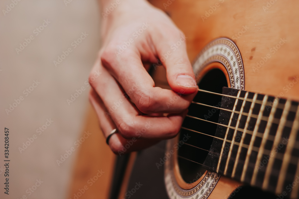 Fototapeta premium The guy is playing the guitar. Close plan