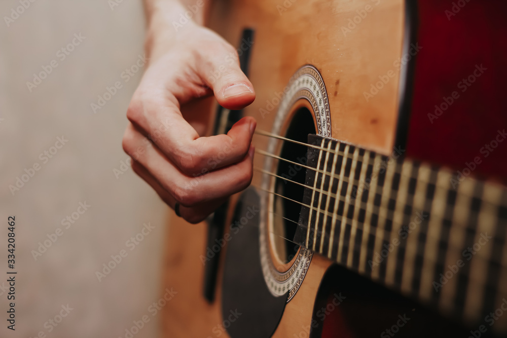 Fototapeta premium The guy is playing the guitar. Close plan