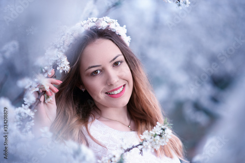 Happy smiling pretty young woman with spring flowers at garden