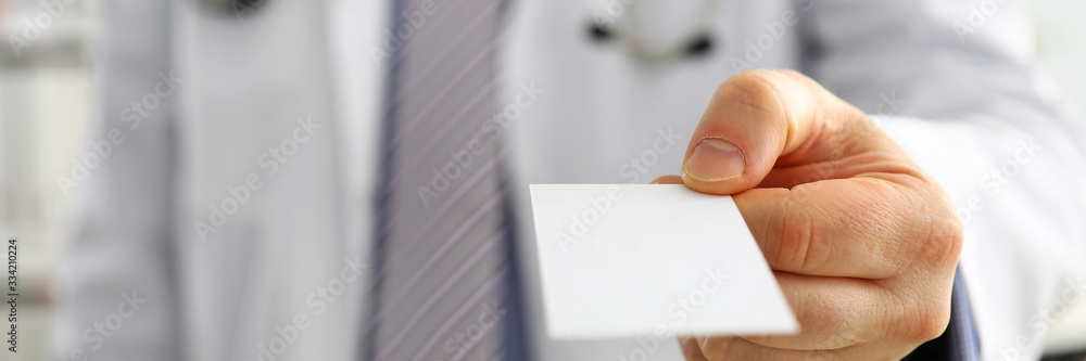 Male physician hand holding and giving white blank calling card Male physician hand holding and giving white blank calling card