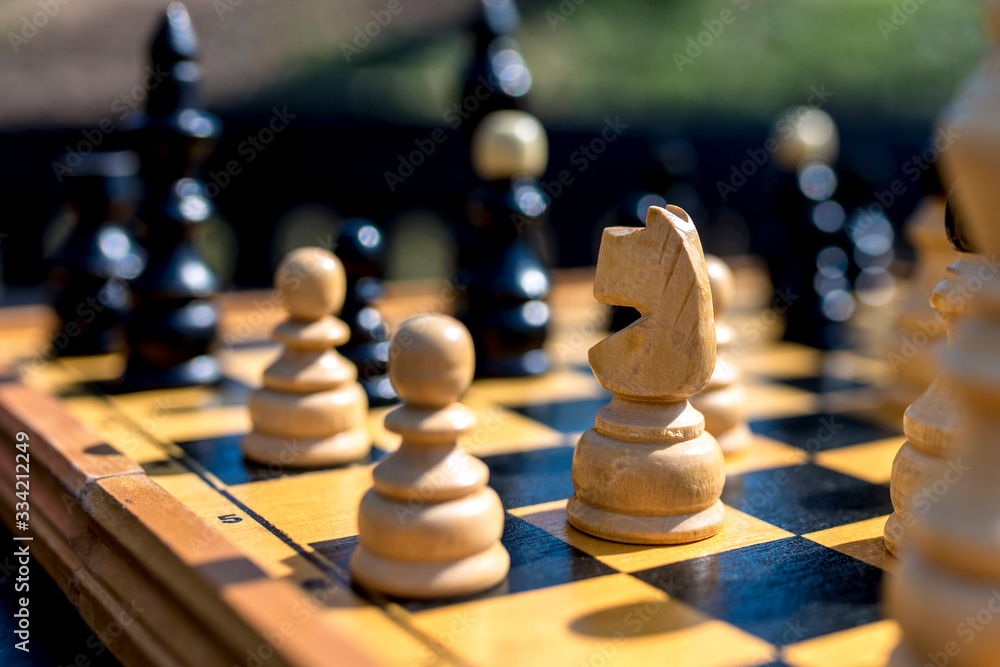 Closeup of wooden chess pieces on a chessboard outdoor in summer park Closeup of wooden chess pieces on a chessboard outdoor in summer park