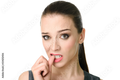 Charming confused young woman with standing and biting nails over white background