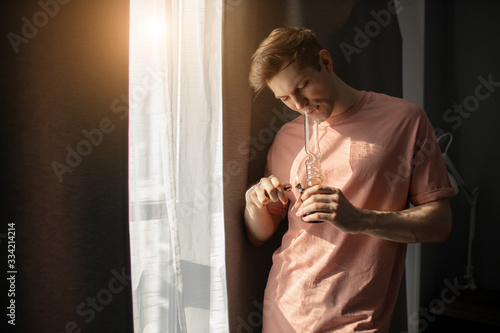 young caucasian man smokes cannabis, medican marijuana using Bong, legalization of marijuana in the world, drug treatment concept. man suffer from addiction photo